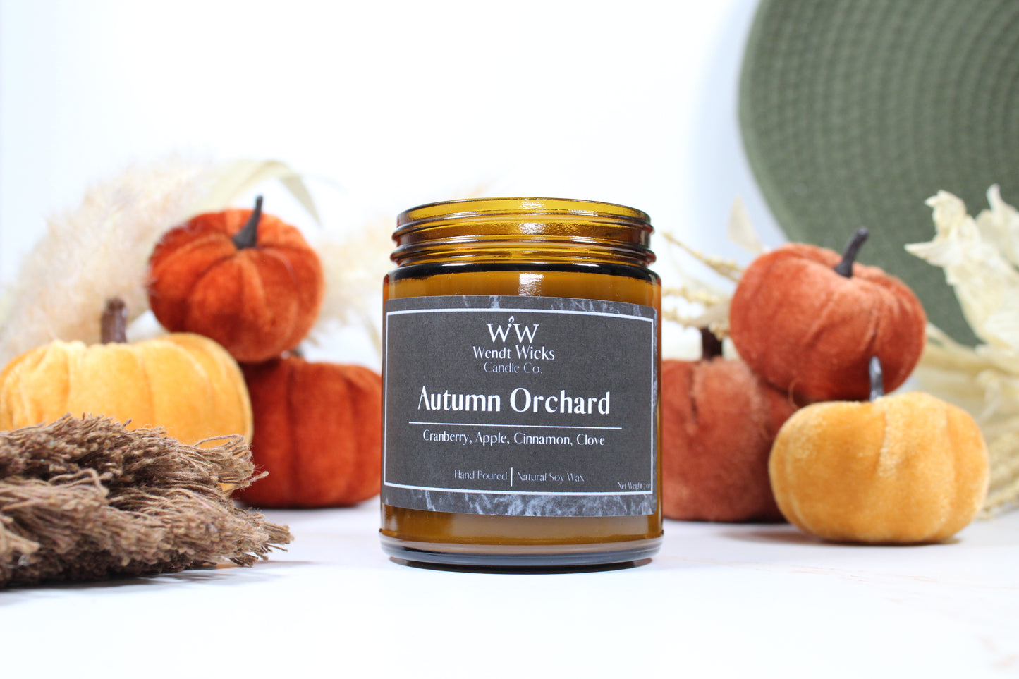 Wendt Wicks amber glass jar candle. Candle labeled 'Autumn Orchard' with pumpkins and decorative Autumn elements on a white background