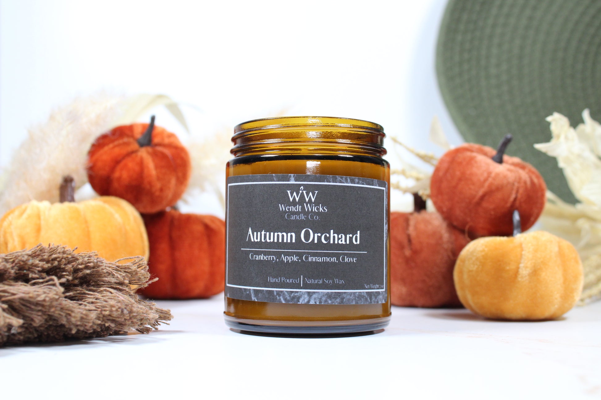 Wendt Wicks amber glass jar candle. Candle labeled 'Autumn Orchard' with pumpkins and decorative Autumn elements on a white background