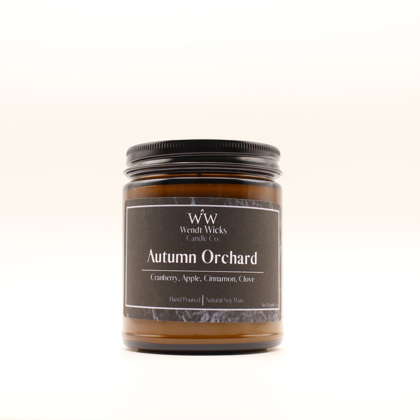 Wendt Wicks amber glass jar candle with black lid. Candle labeled 'Autumn Orchard'  on a white background