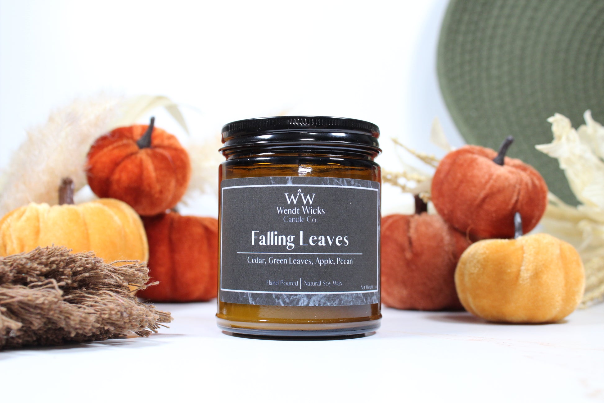 Wendt Wicks amber glass jar candle with black lid. Candle labeled 'Falling Leaves' with pumpkins and decorative Autumn elements on a white background