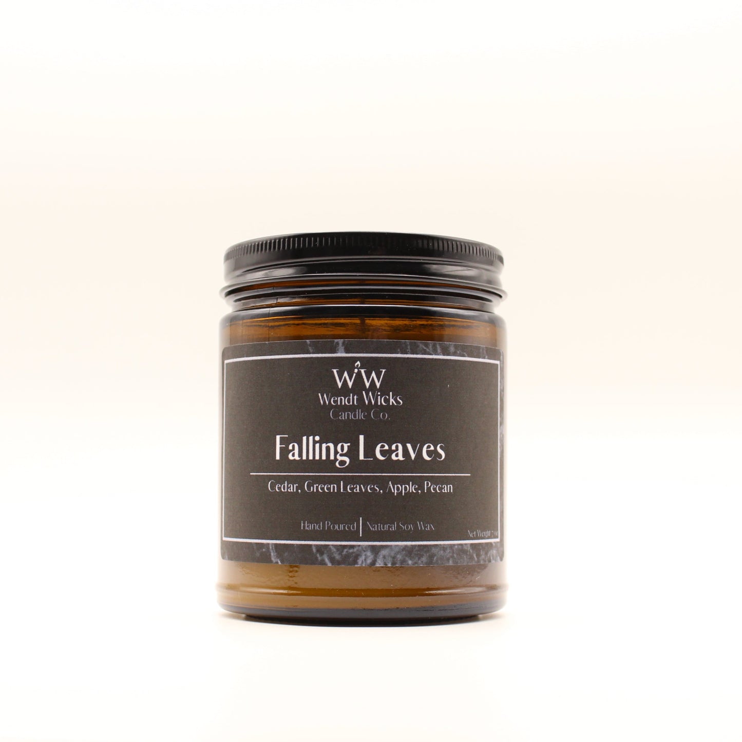 Wendt Wicks amber glass jar candle with black lid. Candle labeled 'Falling Leaves' on a white background