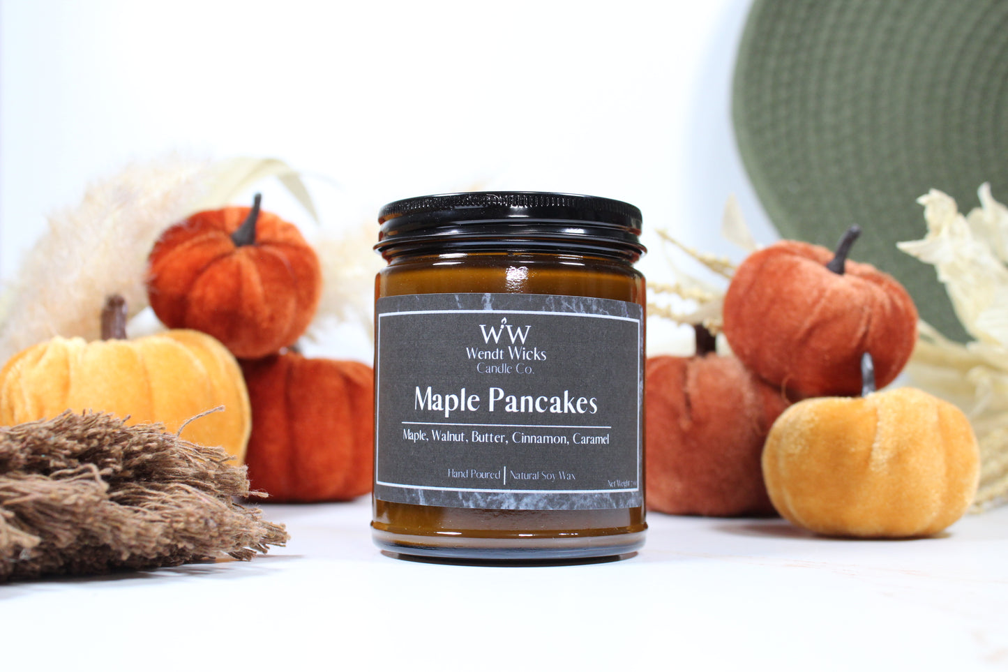 Wendt Wicks amber glass jar candle with black lid. Candle labeled 'Maple Pancakes' with pumpkins and decorative Autumn elements on a white background