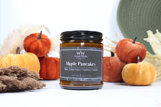 Wendt Wicks amber glass jar candle with black lid. Candle labeled 'Maple Pancakes' with pumpkins and decorative Autumn elements on a white background