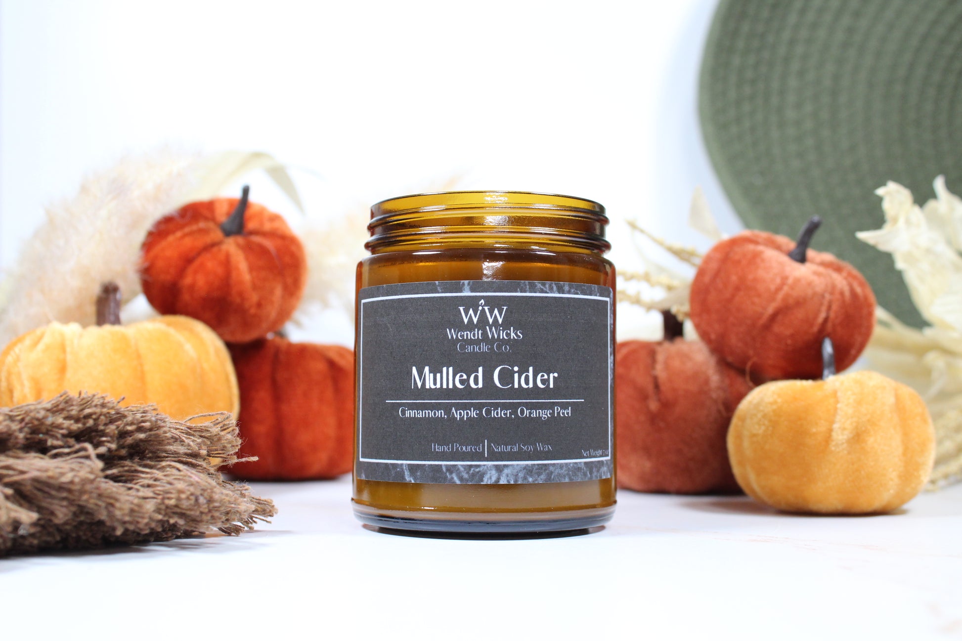 Wendt Wicks amber glass jar candle. Candle labeled 'Mulled Cider' with pumpkins and decorative Autumn elements on a white background